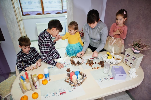 Mother with four kids makes a wreath for Christmas Eve and crafting decorating. New Year celebration.