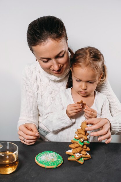 Mother with girl decorating gingerbread cookies for christmas