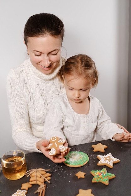 Mother with girl decorating gingerbread cookies for christmas