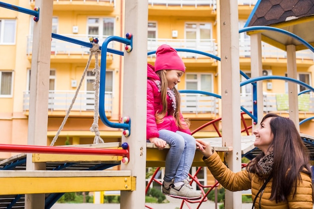 Mother with girl at playground Woman helps her daughter