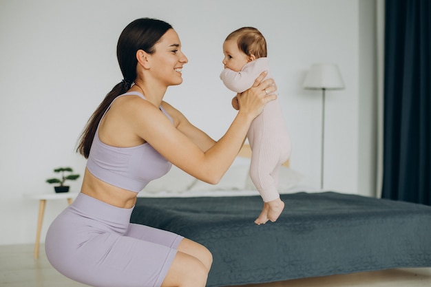 Mother with her baby daughter practice yoga at home