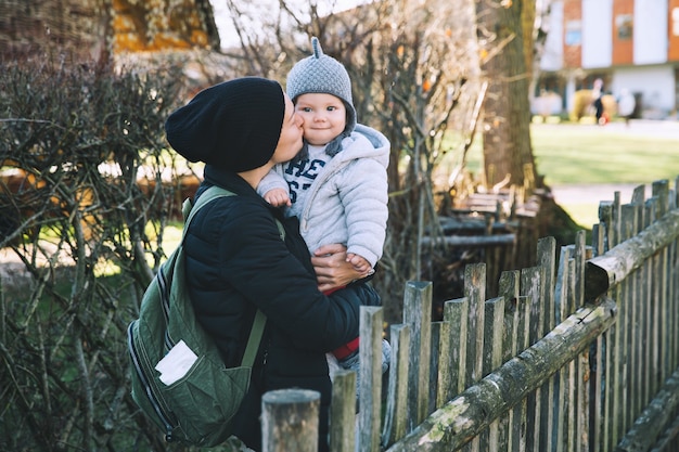 Mother with her baby dressed in warm clothes walking on a sunny day outdoors