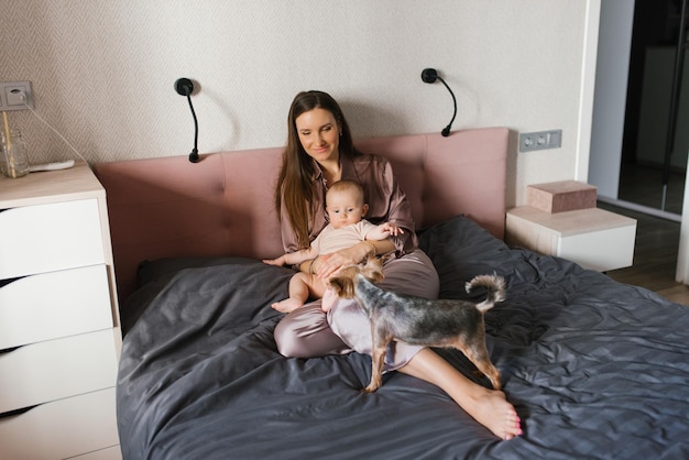 Mother with her baby song playing in the bed playing with their dogs