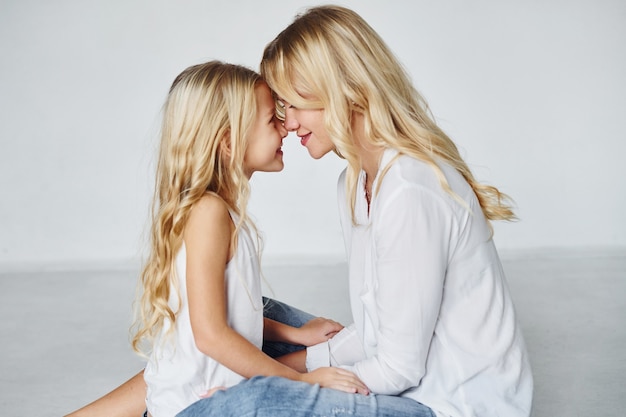 Mother with her daughter together in the studio with white background.