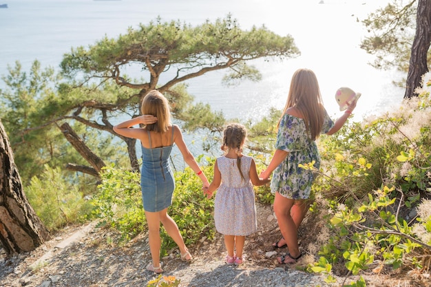 Mother with her daughters holding hands and looking at the sea