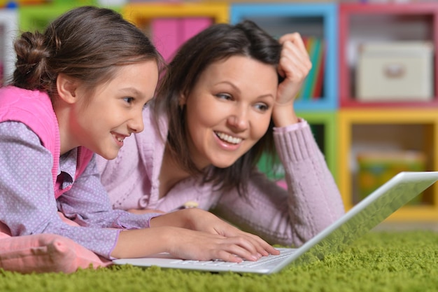 Mother with her little daughter using laptop