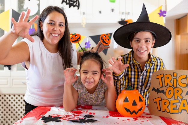 Mother with her two kids posing funny while celebrating Halloween party. Single parent family concept.