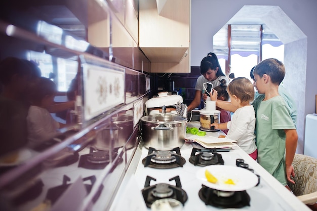 Mother with kids cooking at kitchen happy children's moments Work with a blender