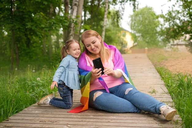 Mother with an LGBT flag and little daughter take selfies