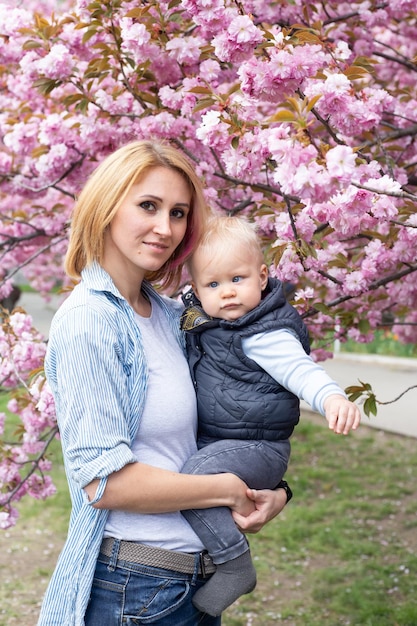 Mother with little son in the park walk near the sakura tree