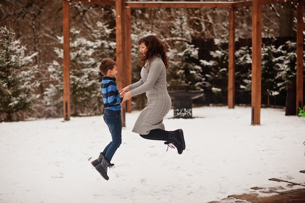 Mother with son jumping in winter day spending time together