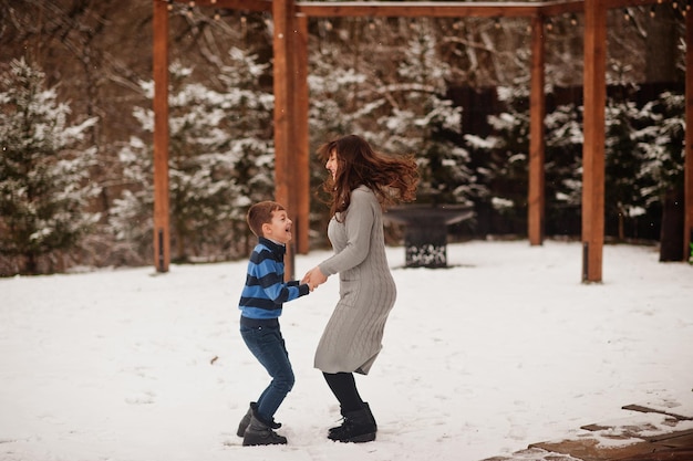 Mother with son jumping in winter day spending time together