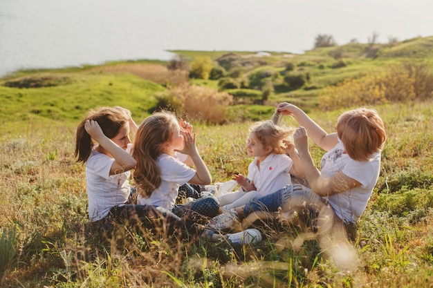 A mother with three daughters sits in the grass on the beach in the summer