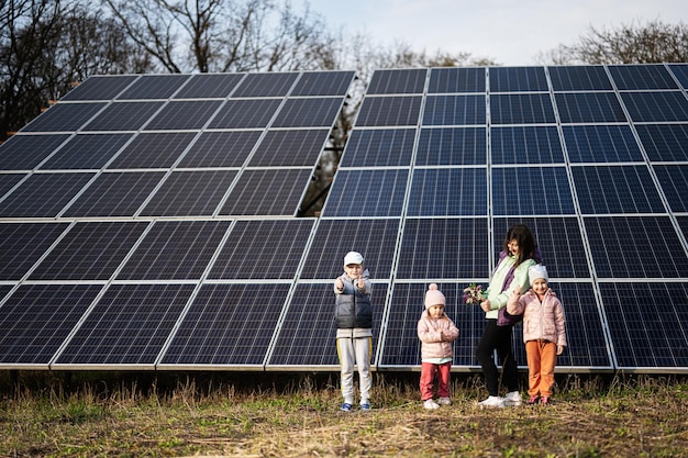 Mother with three kids on the background of solar panels Eco energy