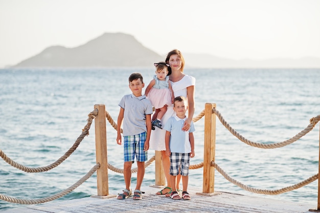 Mother with three kids at Turkey resort against Mediterranean sea stand on the pier.