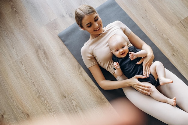 Mother with toddler daughter exercising on mat