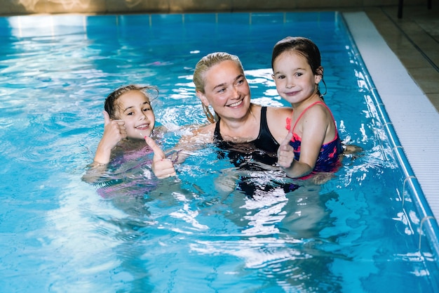 Mother with two daughters having fun in indoor swimming-pool