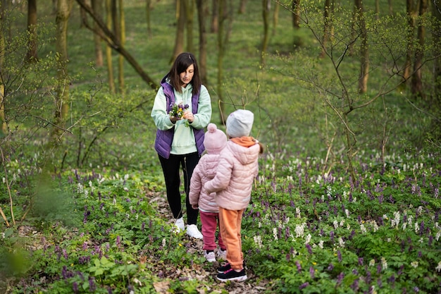 Mother with two daughters pluck a spring bouquet of flowers on forest Outdoor leisure concept