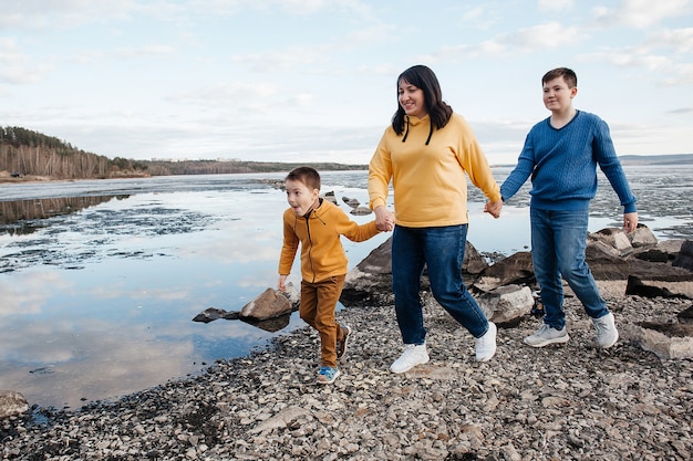 A mother with two sons on the riverbank. Mom and her sons are running. Outdoor recreation.