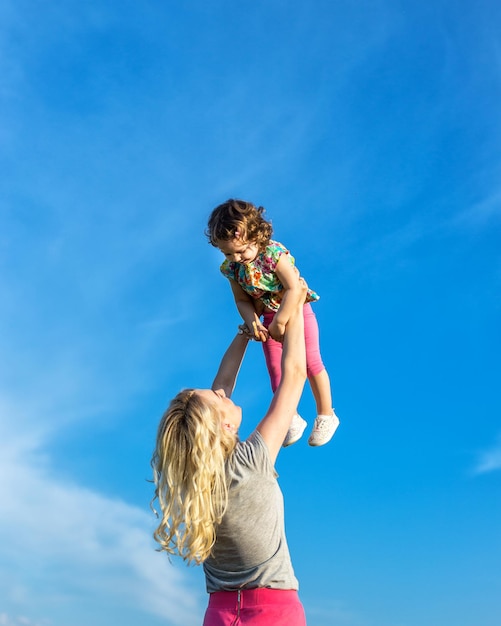 A mother woman plays with a child in nature lifting and tossing him in her