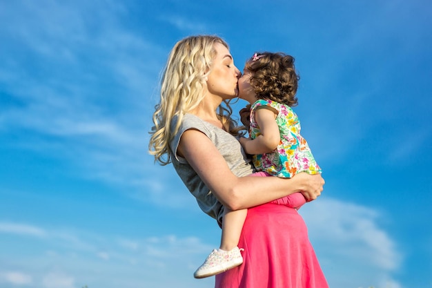 A mother woman plays with a child in nature lifting and tossing him in her