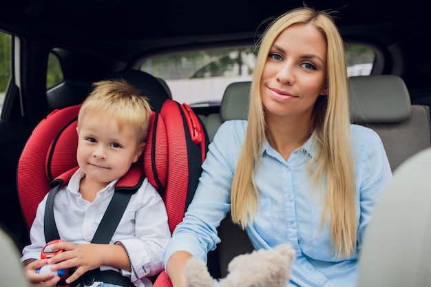 Mother worried about her children's safety in a car Son near mom Babes sitting inside modern auto People look camera The idea of safe traffic