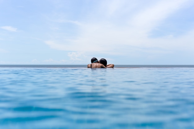 Photo mother and young son relax in swimming pool looking over the ocean on summer vacation.