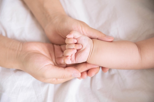 Mothers hand holding newborn babys barefoot