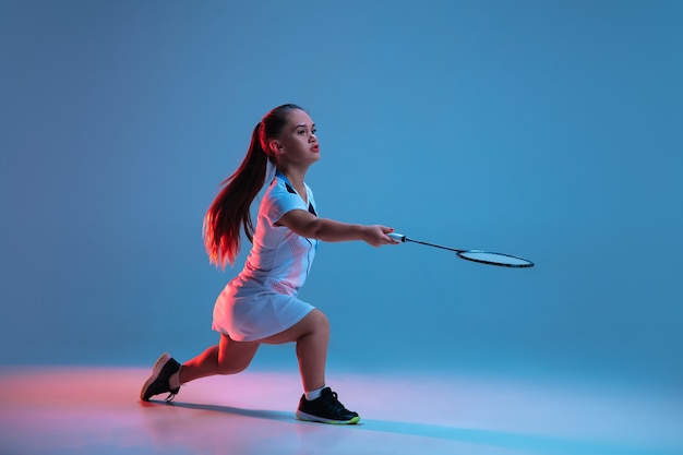 Motion. Beautiful dwarf woman practicing in badminton isolated on blue background in neon light. Lifestyle of inclusive people, diversity and equility. Sport, activity and movement. Copyspace for ad.