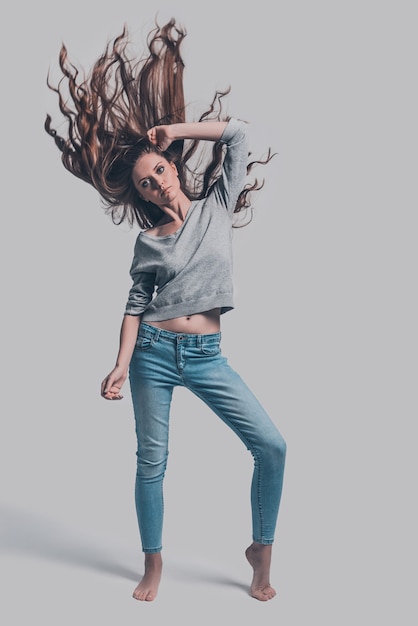 In motion. Full length studio shot of attractive young woman with tousled hair posing 