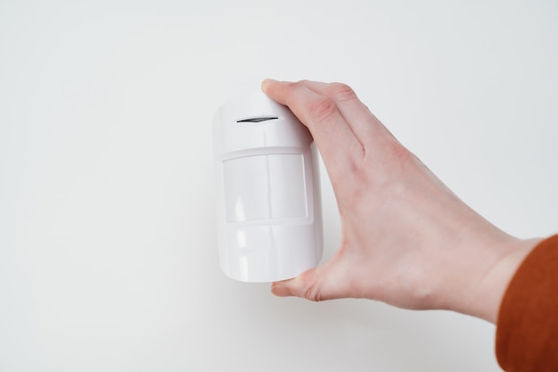 Motion sensor in hand on white background. device that tracks the movement of objects. It is used to automate operation of electrical appliances, surveillance video cameras, alarms and security system