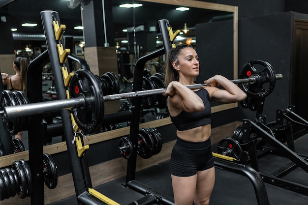 Motivated young female athlete doing shoulder press exercise in gym