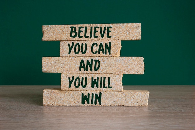 Photo motivational concept believe you can and you will win on brick blocks beautiful green background