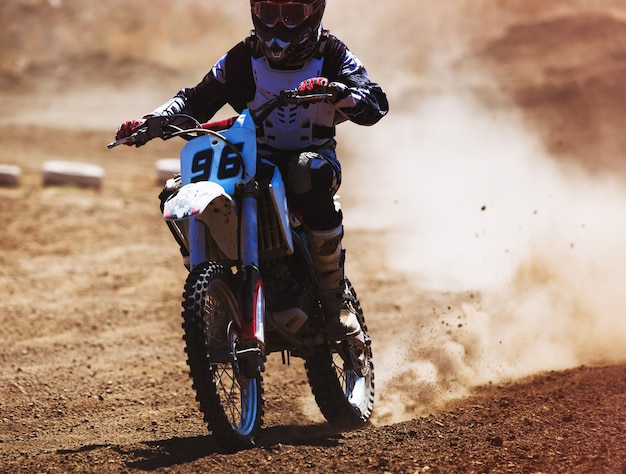 Motocross racer accelerating in dust track Tinted photo