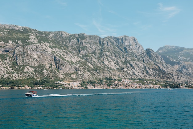 Motor boat with tourists on board sails along the kotor bay against mountains