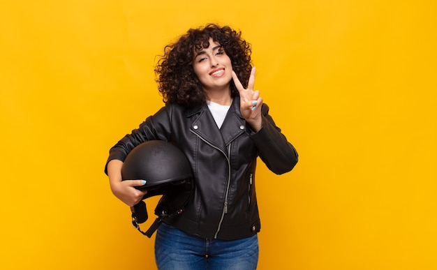 motorbike rider woman smiling and looking friendly, showing number two or second with hand forward, counting down