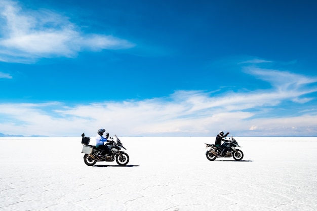 Motorbikers and car riding among sunshine salar de uyuni