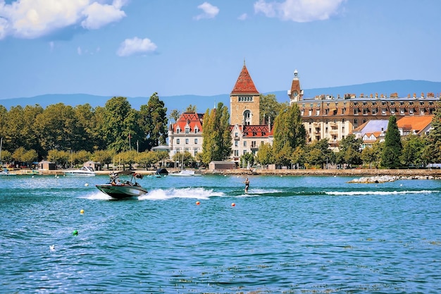 Motorboat and man wakeboarding at Lake Geneva embankment near Chateau Ouchy in Lausanne, Switzerland.