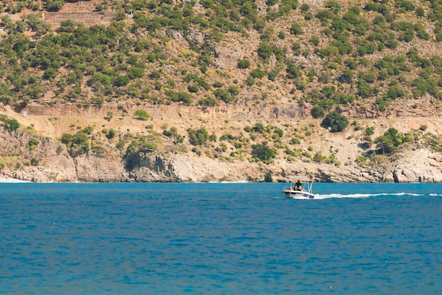 Motorboat with man on the background of the rocky coast