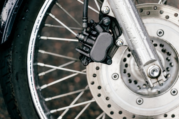 Motorcycle wheel with disk brakes system and metal spokes. Closeup detailed photo of motorbike forks and tire. Different parts of two-wheeled vehicle.  Transportation. Modern driving technologies