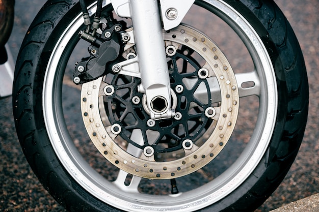 Motorcycle wheel with disk brakes system and metal spokes. Closeup detailed photo of motorbike forks and tire.  Transportation. Modern driving technologies