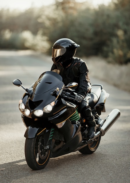 Motorcyclist in a helmet on a motorcycle on a country road. Guy driving a bike during a trip. Riding a modern sports motorcycle on the highway