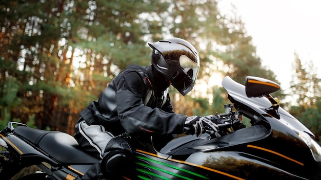 Motorcyclist in helmet rides on the road on modern black motorcycle. Sport bike. Copy space for your customized text. Motorcyclist in leather protective gear