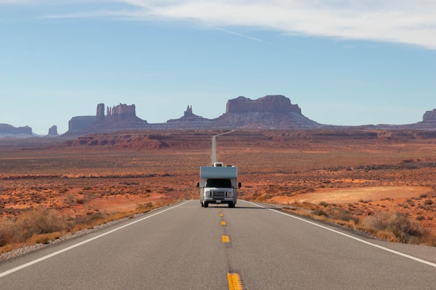 Motorhome roadtripping with Monument Valley behind under blue sky