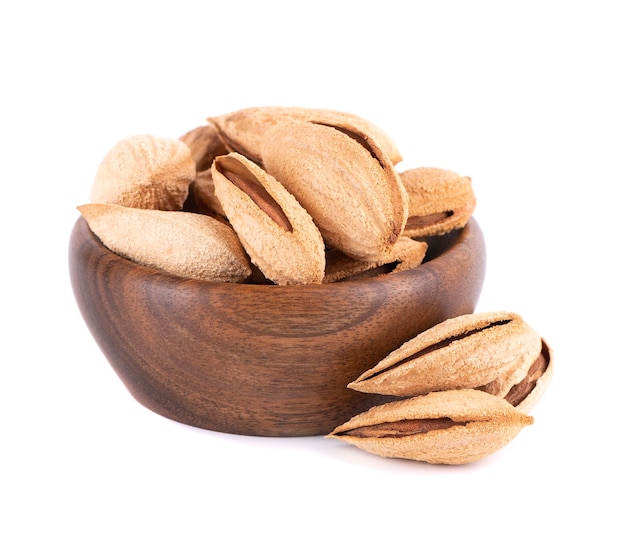 Mountain almonds in wooden bowl isolated on white background Uzbek wild almonds