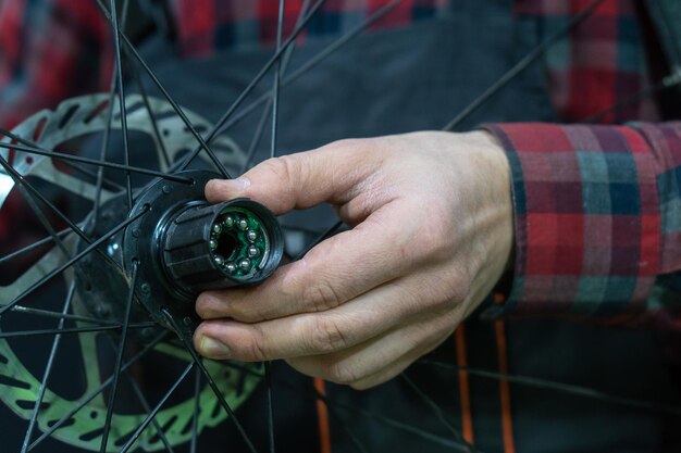 Mountain bike repair Bike mechanic in the workshop Replacing grease and bicycle hub bearings The mechanic is holding a wheel in his hand Bearing closeup