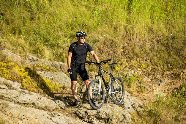 Mountain biker with a bicycle on a rock. Motivation and inspiration for adventure.