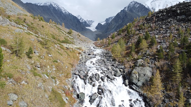 Mountain flowing stream and waterfall in the forest Picturesque aerial drone landscape view Altai mountains