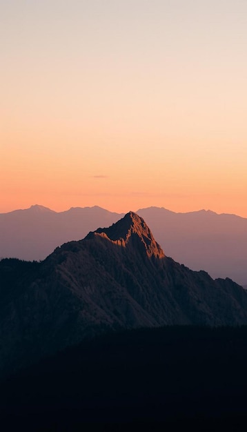 Photo a mountain is silhouetted against a sunset sky