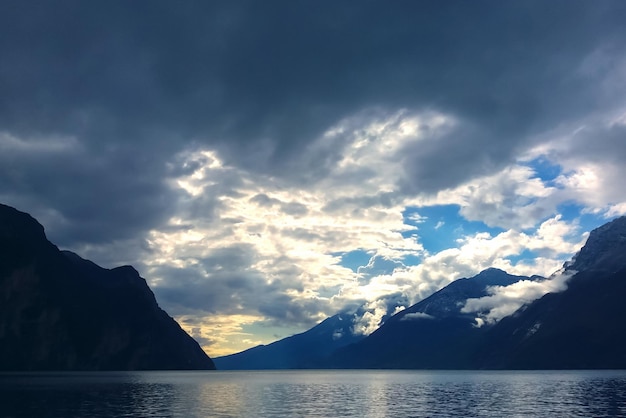 Mountain lake with dramatic clouds in stormy sky at blue twilight